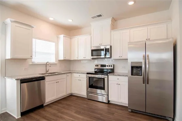 a kitchen with white cabinets stainless steel appliances and sink