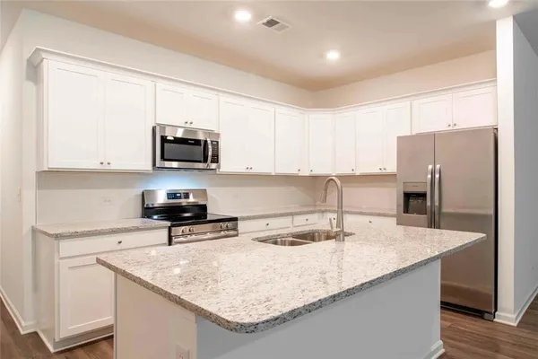 a kitchen with stainless steel appliances granite countertop a sink a stove and a refrigerator
