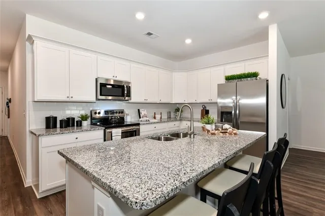 a kitchen with stainless steel appliances granite countertop a table chairs sink refrigerator and microwave