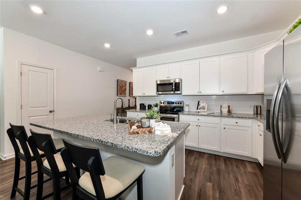 12006 Crosswicks Road, Unit SUNBURST Union City, GA 30291 - Photo 10 of 24 a kitchen with stainless steel appliances granite countertop a stove a sink dishwasher a microwave oven with a dining table and chairs