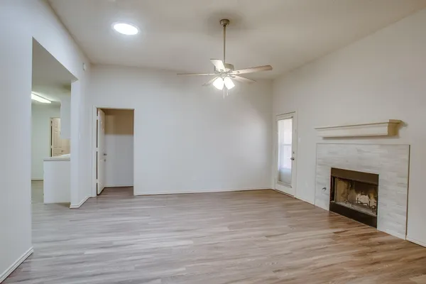 a view of an empty room with wooden floor fireplace and a window