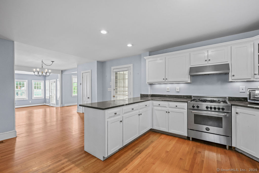 88 Powder Hill Road Middlefield, CT 06455 - Photo 20 of 40 a kitchen with granite countertop a stove top oven a sink and white cabinets with wooden floor