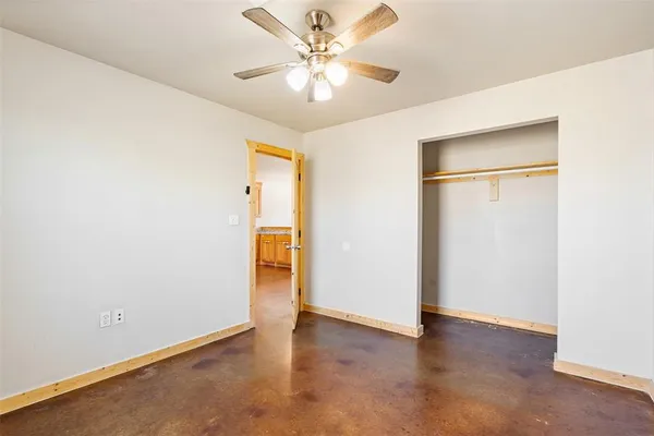 an empty room with closet and a chandelier fan