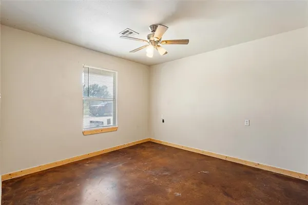 an empty room with windows and fan
