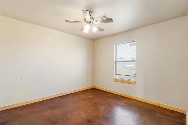 an empty room with chandelier fan and windows