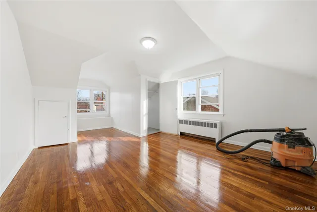 a view of an empty room with window and wooden floor