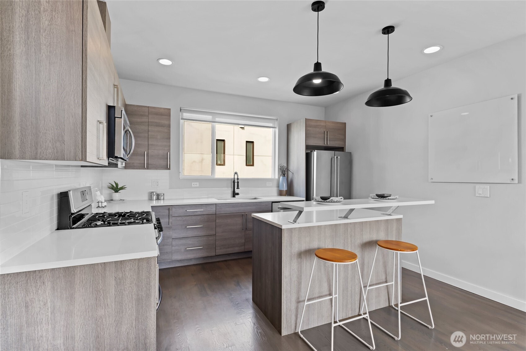 2653 Northwest 64th Street, Unit A Seattle, WA 98107 - Photo 7 of 32 a kitchen with kitchen island stainless steel appliances a stove a sink and chairs