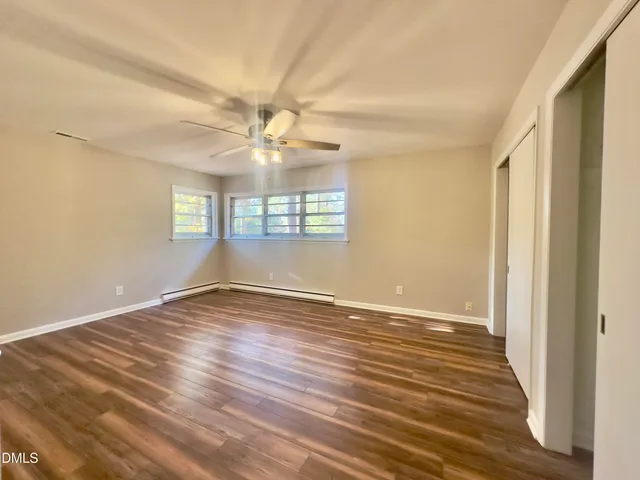 a view of an empty room with wooden floor and a window