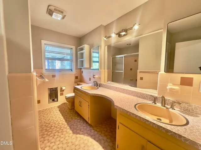 a spacious bathroom with a granite countertop double vanity sink a mirror and a shower