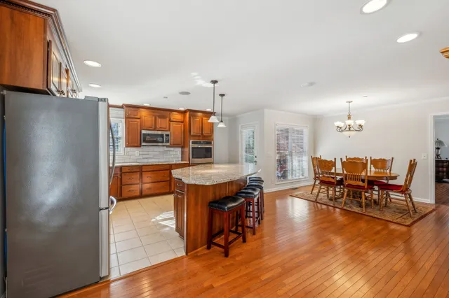a kitchen with stainless steel appliances granite countertop a table chairs and a refrigerator