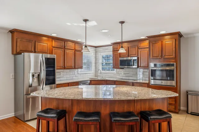a kitchen with stainless steel appliances granite countertop a kitchen island a table and chairs in it