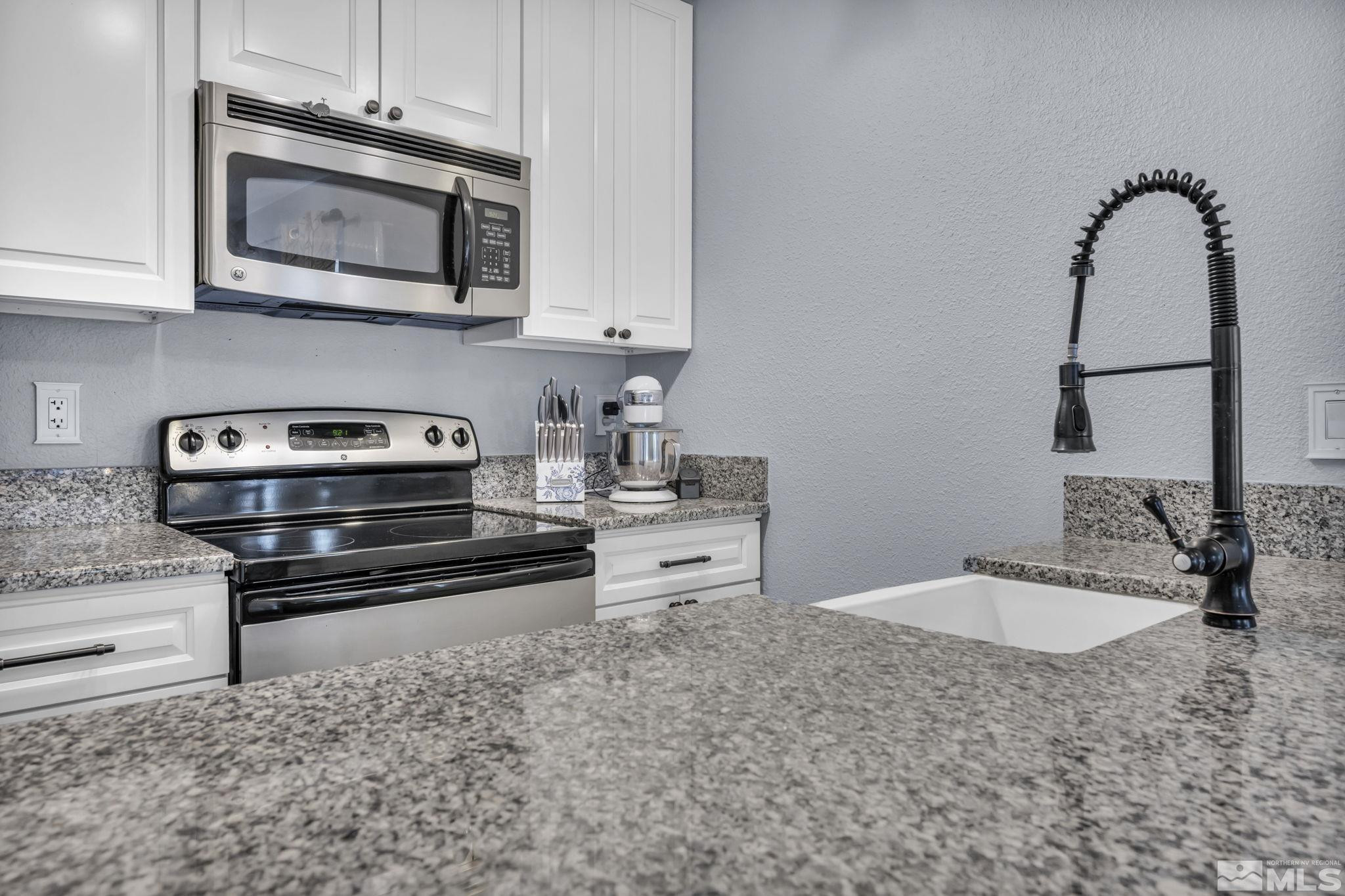 4721 Reggie Road Reno, NV 89502 - Photo 11 of 33 a kitchen with stainless steel appliances granite countertop a sink and a stove top oven