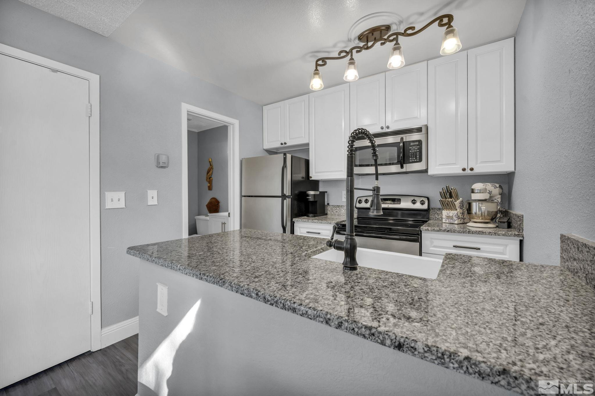 4721 Reggie Road Reno, NV 89502 - Photo 13 of 33 a kitchen with stainless steel appliances granite countertop a sink refrigerator and microwave