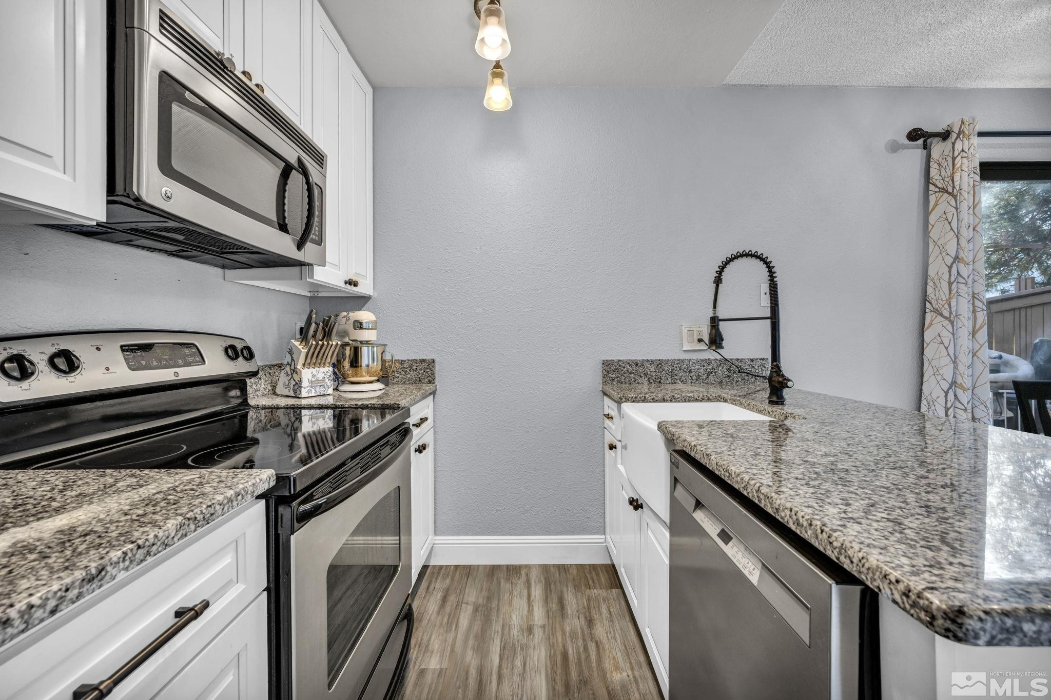 4721 Reggie Road Reno, NV 89502 - Photo 7 of 33 a kitchen with stainless steel appliances granite countertop a stove microwave and sink