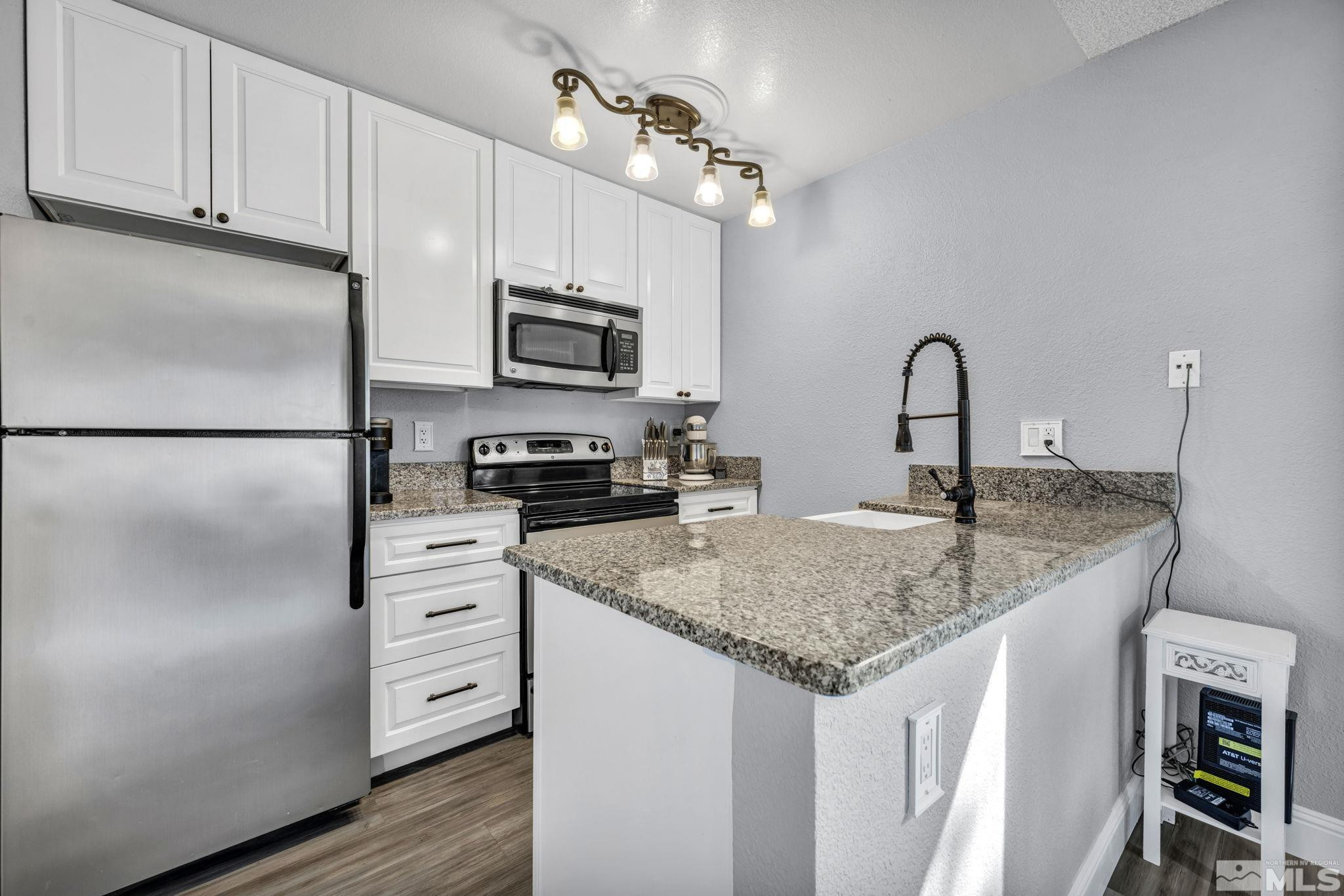 4721 Reggie Road Reno, NV 89502 - Photo 10 of 33 a kitchen with stainless steel appliances granite countertop a sink refrigerator and microwave
