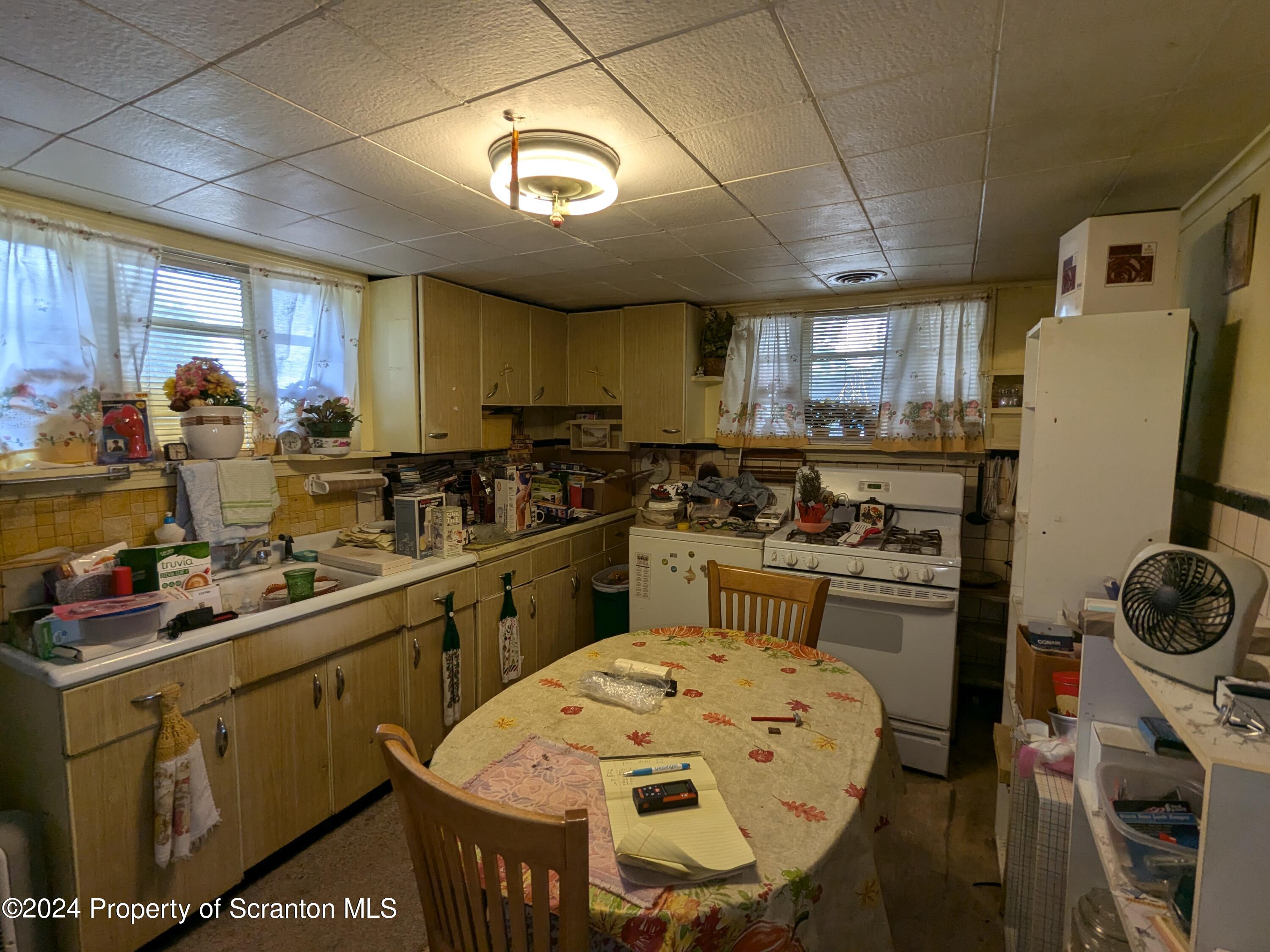 909 Battle Street Scranton, PA 18508 - Photo 6 of 11 a kitchen with a sink a stove cabinets dining table and chairs