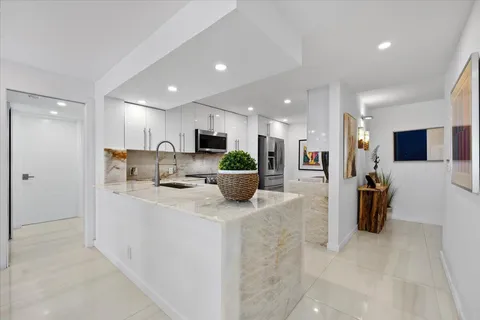 a kitchen with stainless steel appliances kitchen island granite countertop a refrigerator and a sink