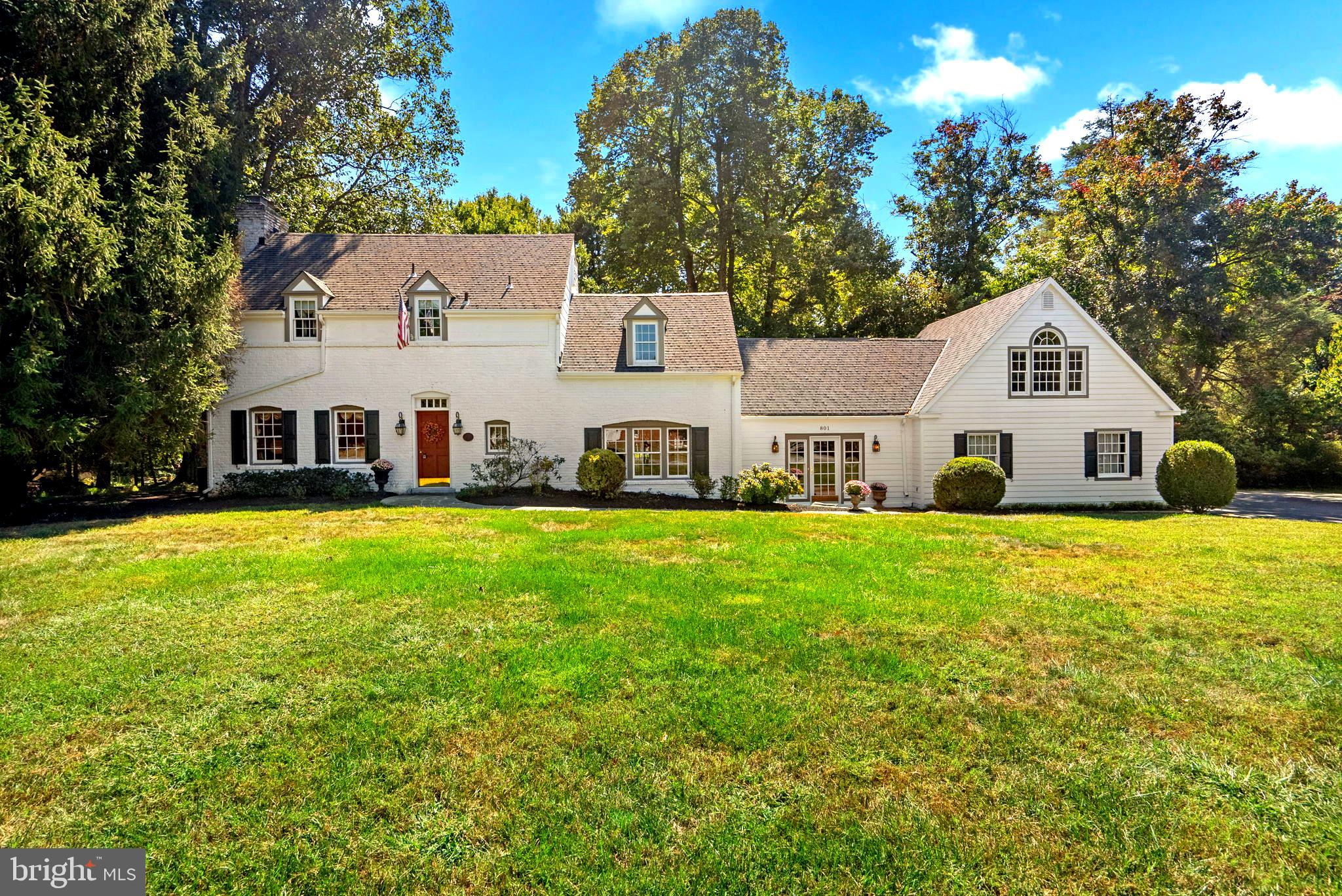 a view of a white house with a big yard and large trees