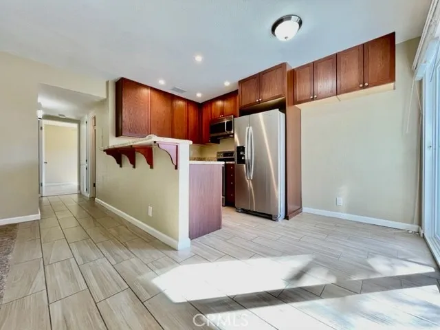 a view of a refrigerator in kitchen and an empty room