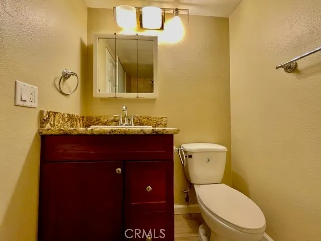 a bathroom with a granite countertop toilet sink and mirror