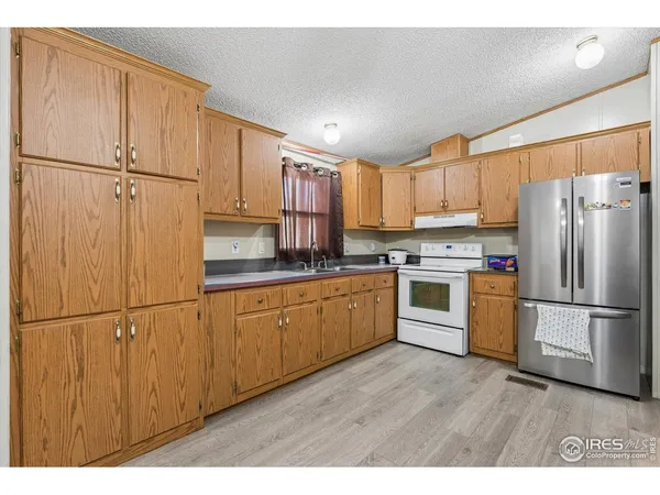 a kitchen with a refrigerator a stove top oven and cabinets