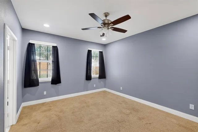 an empty room with windows and fan