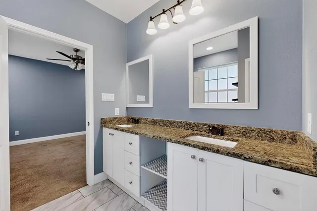 a bathroom with a granite countertop sink and a mirror