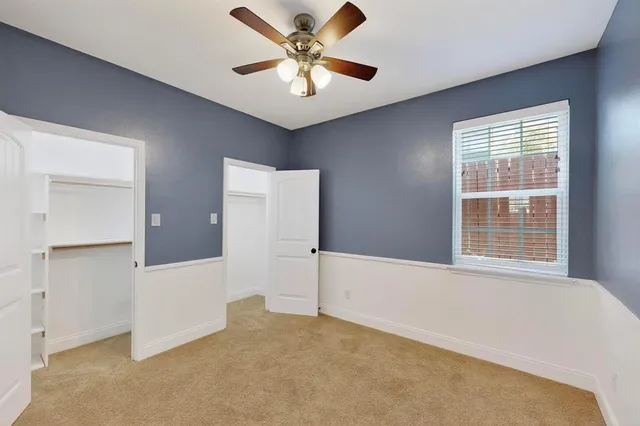 a view of an empty room with window and a kitchen
