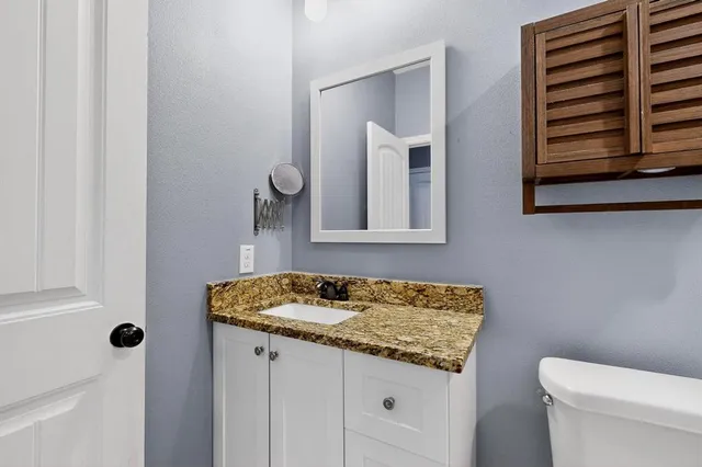 a bathroom with a granite countertop sink and a toilet