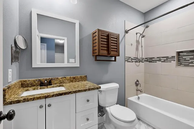 a bathroom with a granite countertop sink toilet and shower