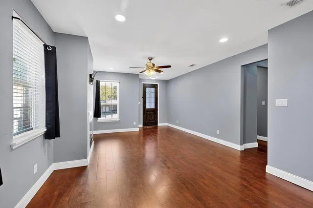 a view of an empty room with wooden floor and a window