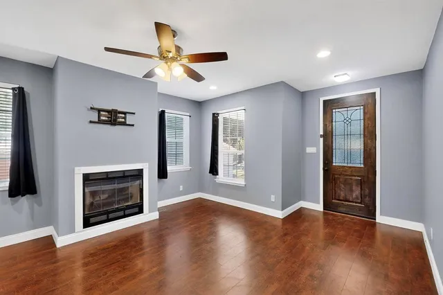 a view of an empty room with wooden floor fireplace and a window