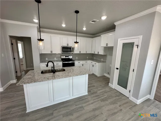 a kitchen with stainless steel appliances granite countertop a refrigerator a sink a stove a microwave and wooden floor