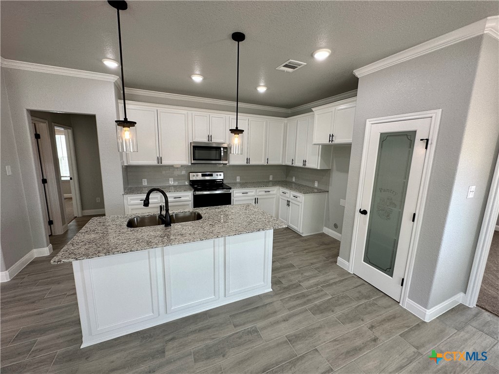 a kitchen with stainless steel appliances granite countertop a refrigerator a sink a stove a microwave and wooden floor