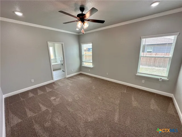 an empty room with a chandelier fan and windows