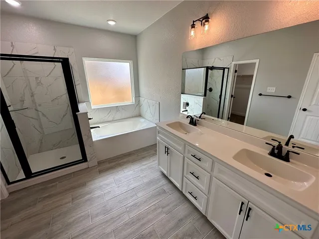 a bathroom with a double vanity sink a mirror and a bathtub