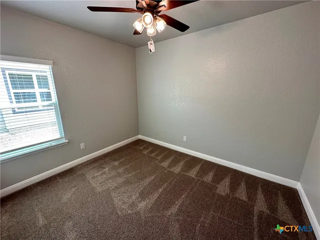 an empty room with chandelier fan and windows