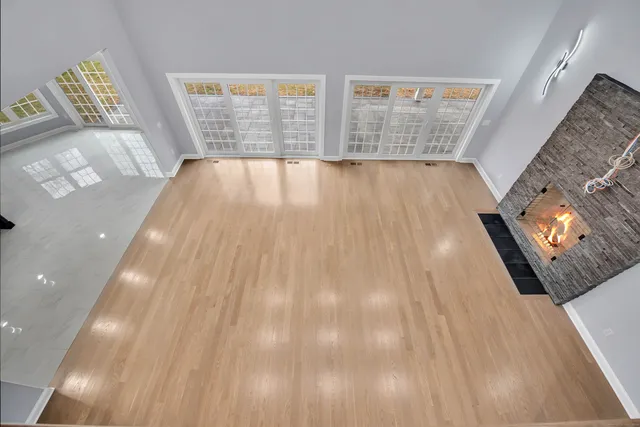 a view of an empty room with wooden floor and windows