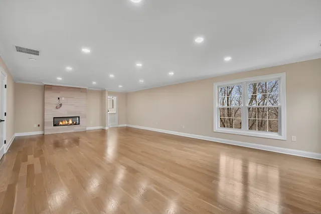 a view of an empty room with a window and wooden floor