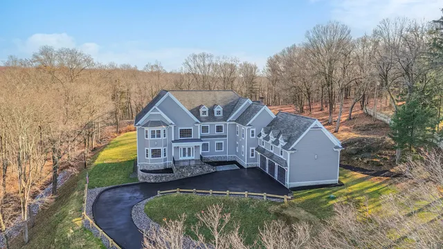 a view of a house with a small yard and large trees