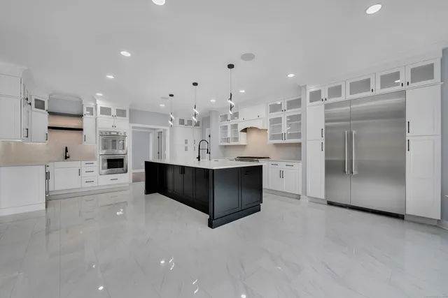 a large white kitchen with a large counter top stainless steel appliances and cabinets