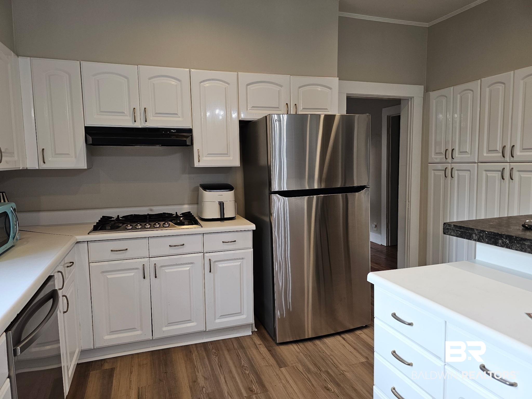 1215 Church Street Mobile, AL 36604 - Photo 6 of 23 Kitchen with crown molding, wood finished floors, under cabinet range hood, stainless steel appliances, and white cabinets