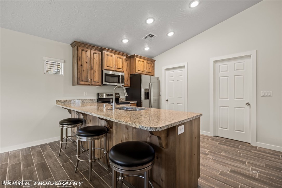 942 Shadow Hawk Ridge Mesquite, NV 89027 - Photo 29 of 67 Kitchen featuring stainless steel appliances, wood finish floors, a breakfast bar area, a sink, and recessed lighting