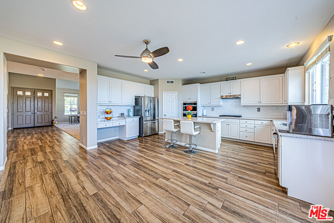 40918 Rise Court Palmdale, CA 93551 - Photo 15 of 45 a kitchen with stainless steel appliances granite countertop a refrigerator oven a stove top oven a sink dishwasher and white cabinets with wooden floor
