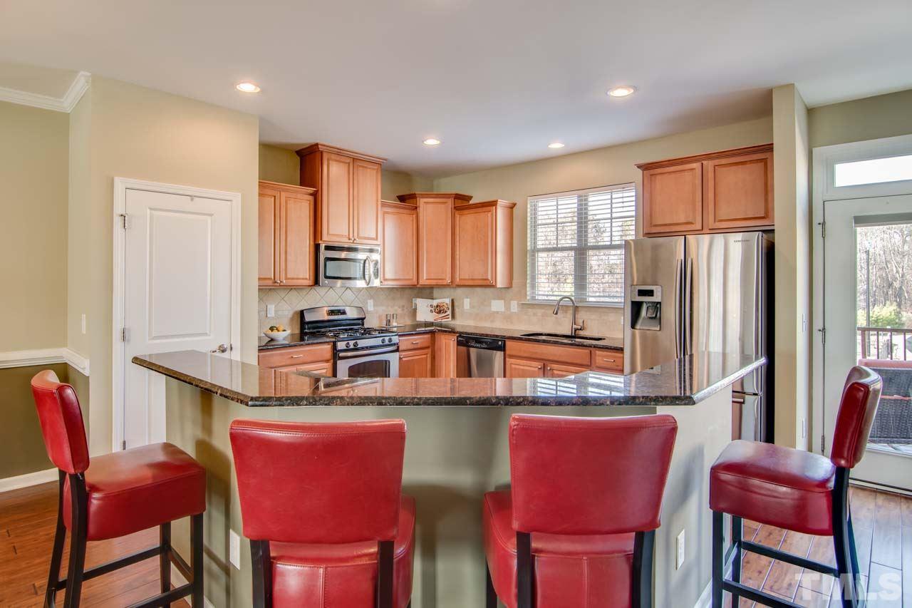 1308 Cornell Place Raleigh, NC 27607 - Photo 9 of 25 a kitchen with stainless steel appliances granite countertop a dining table chairs refrigerator and wooden cabinets