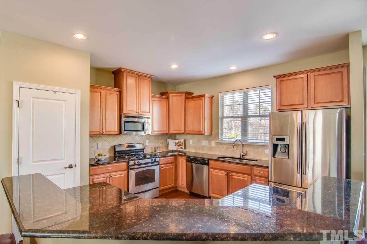 1308 Cornell Place Raleigh, NC 27607 - Photo 10 of 25 a kitchen with stainless steel appliances granite countertop a refrigerator a sink dishwasher a stove and white cabinets with wooden floor