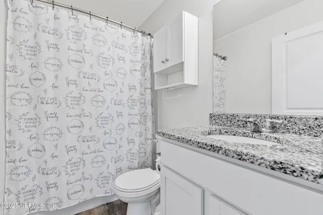 a bathroom with a granite countertop toilet and a sink