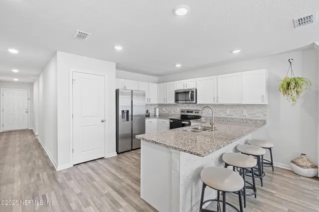 a kitchen with stainless steel appliances granite countertop a sink refrigerator and cabinets