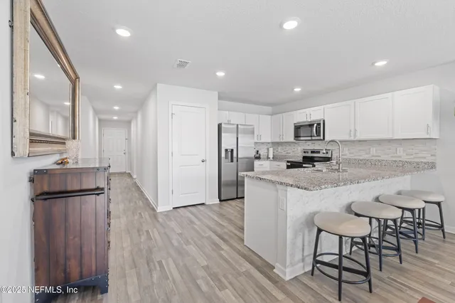 a kitchen with granite countertop a refrigerator and a stove top oven