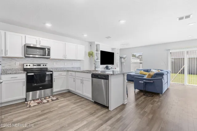 a kitchen with microwave a stove top oven and cabinets